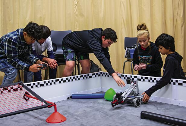 Jezebel Losack (center) leads her team of fellow seventh-graders as the group applies math, engineering, and trial-and-error methods while programming their robot to perform autonomous tasks.