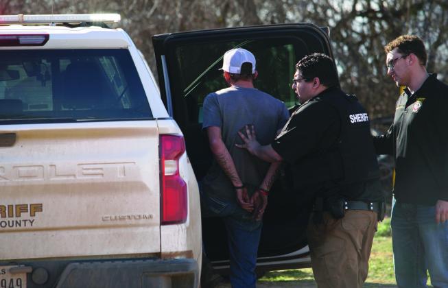 While FCSO employee, Levi Garland looks on, Fisher County Deputy Joseph Benavides detains the driver, fitting the description of a known fugitive suspected of having stolen the ATV, on Monday. The driver was questioned and released. The f ugitive remains at large.