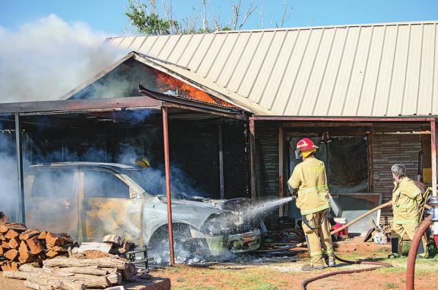 Firefighters work to extinguish Tuesday's fire that started as a vehicle fire and later destroyed a home along County Road 327.