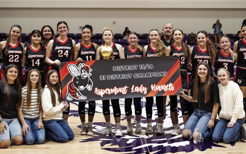 The Aspermont Lady Hornet baskeball team, coaching staff, and managers hoist the Bi-District title after a commanding 66-29 win over Harrold. Photo by: Mark Martinez