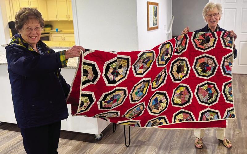 Lenice Dennis and Dot Harris show off one of Ellen Goodwi's quilts, who brought several family quilts to share during her presentation, using them to highlight how quilts preserve memory and history across generations PHOTO BY JEFF HURT