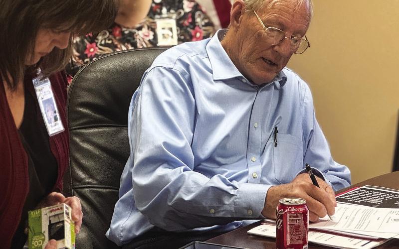 New Stonewall Memorial Hospital District board director Edmond Scott Lucast signs paperwork after taking the oath of office during the board’s Monday, May 11 meeting. PHOTO BY JEFF HURT