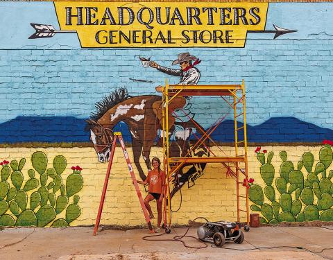 Artist Lexi Haag stands in front of her largest work yet, which graces the the main-street-facing wall of the Headquarters General Store's new location.