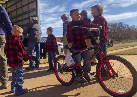 Dressed in matching holiday attire, Methodist Preacher Jeff Sedberry's grandsons (from L to R) Kannon Durham, Stetson Sedberry, Kelton Durham, and Alan Durham help volunteers with the Fisher County Ministerial Alliance and Larry Sauls unload a truckful of donated bicycles this Sunday.