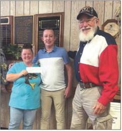 Stonewall Senior Citizens Director Becky Flores and longtime board member, George Abernathy accepts a $500 donation check from County Attorney Riley Branch.
