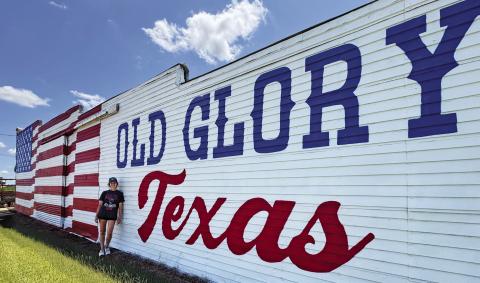Lexi Antonick stands in front of the newly refreshed Old Glory mural she restored.