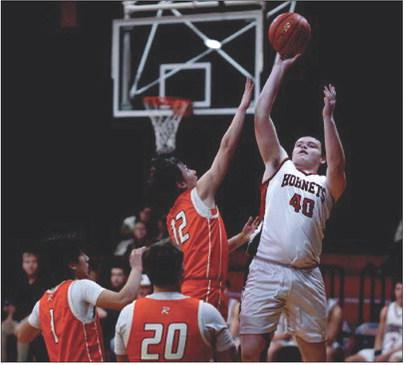 Aspermont's Austin Ingram puts up a shot over Hammer defenders during the Hornets 79-36 win over Rotan last Friday night. Photo by: Mark Martinez