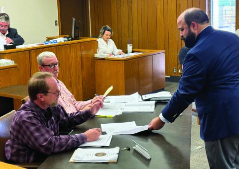 Jake Lederle, partner with Wetsel &amp; Lederle LLP review eligibility requirements for participating in tax abatements with commissioners Preston Martin and Micah Evans during Fisher County Court's August meeting.