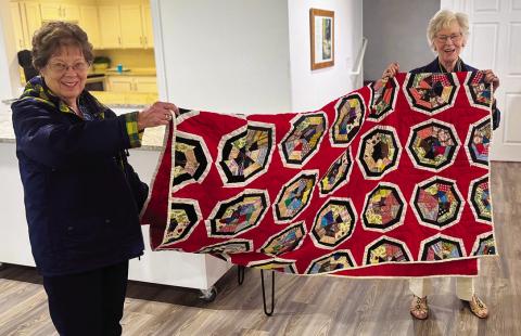 Lenice Dennis and Dot Harris show off one of Ellen Goodwi's quilts, who brought several family quilts to share during her presentation, using them to highlight how quilts preserve memory and history across generations PHOTO BY JEFF HURT