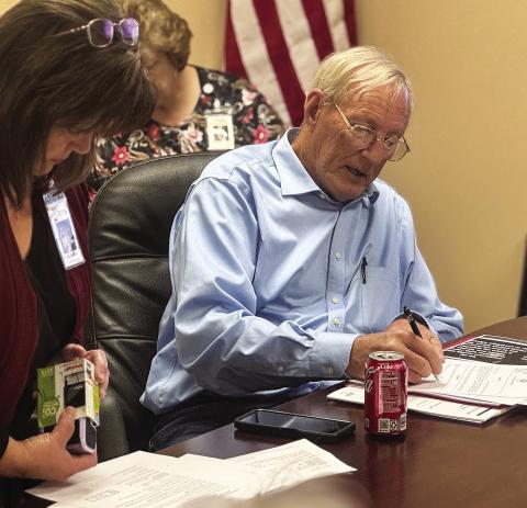 New Stonewall Memorial Hospital District board director Edmond Scott Lucast signs paperwork after taking the oath of office during the board’s Monday, May 11 meeting. PHOTO BY JEFF HURT