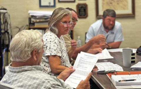 Rotan City Council members review sealed bids for repairing and renovating the cities three main water storage tanks during the July meeting.