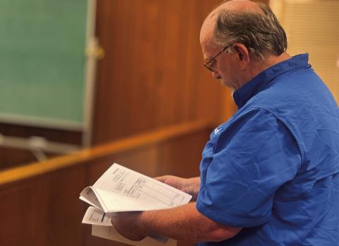 Fisher County Sheriff Pat Dickson reviews proposed bids for new patrol vehicles during Monday’s commissioners court meeting.