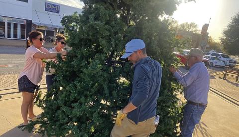 Rotan Community Service League members, Blaire Helms and Samantha Pipes (pictured left) along with Garreth Pipes and Glen Copeland (pictured Right) begins holiday preparations with the community Christmas tree going up on Monday in downtown Rotan.