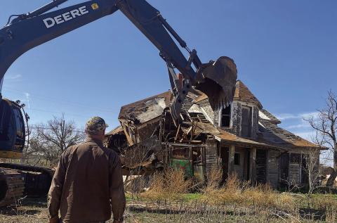 Equipment operator and contributor to the City of Aspermont's cleanup project, Michael Mims looks on as workers demolish one of the city's largest dilapidated structures on Monday. (PHOTO BY JEFFHURT)