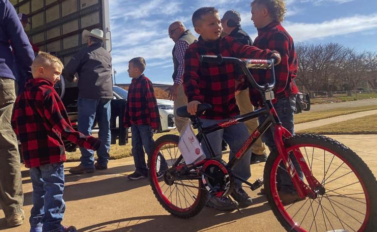 Dressed in matching holiday attire, Methodist Preacher Jeff Sedberry's grandsons (from L to R) Kannon Durham, Stetson Sedberry, Kelton Durham, and Alan Durham help volunteers with the Fisher County Ministerial Alliance and Larry Sauls unload a truckful of donated bicycles this Sunday.