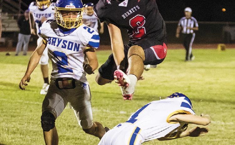 Left: Aspermont's Grayson English Hurdles a Cowboy defender on his way to the endzone during the Hornets' contest with Bryson last