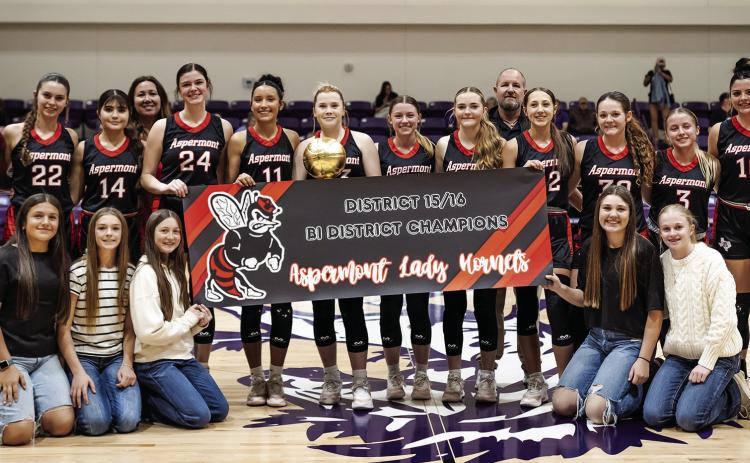 The Aspermont Lady Hornet baskeball team, coaching staff, and managers hoist the Bi-District title after a commanding 66-29 win over Harrold. Photo by: Mark Martinez