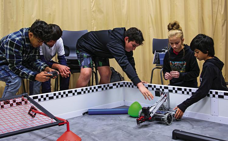 Jezebel Losack (center) leads her team of fellow seventh-graders as the group applies math, engineering, and trial-and-error methods while programming their robot to perform autonomous tasks.