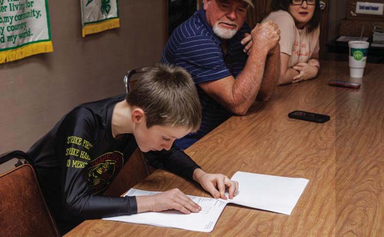 Not quite voting age, Roby CISD student Carson Evans, son of Precinct 4 Commissioner Micah Evans, reads the results of early voting while Fisher County Precinct 1 Commissioner Gordon Pippin looks on. PHOTO BY JEFF HURT
