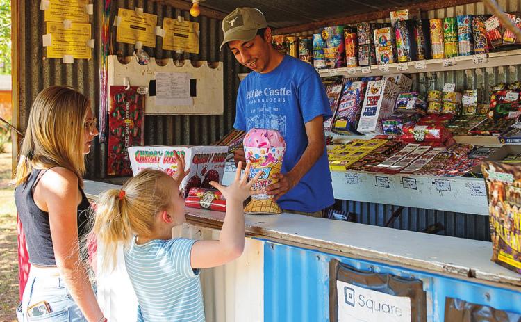 Drew Yanez helps pick out the perfect fireworks for Riley and Everleigh Hurt at the Marinez Family Fireworks stand located at 812 N. Cleveland in Rotan.