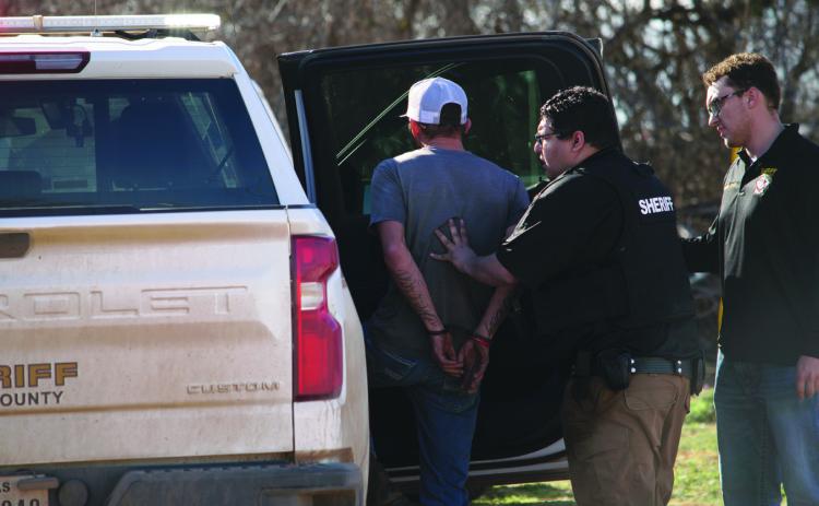 While FCSO employee, Levi Garland looks on, Fisher County Deputy Joseph Benavides detains the driver, fitting the description of a known fugitive suspected of having stolen the ATV, on Monday. The driver was questioned and released. The f ugitive remains at large.