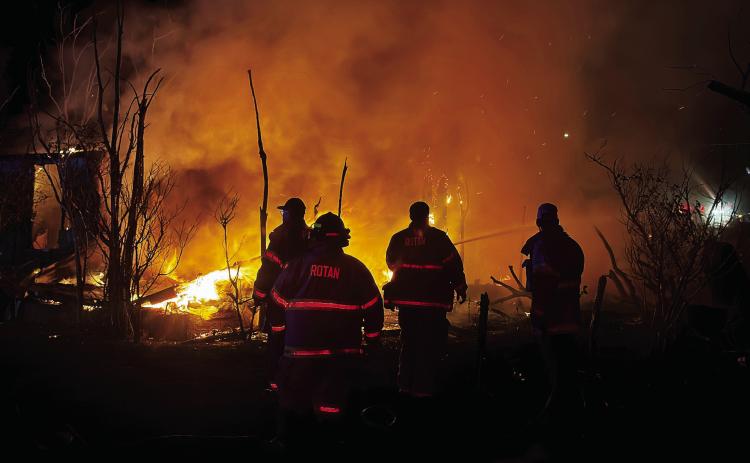 Rotan and Roby fire personnel work to prevent the spread of a fire that destroyed a vacant house on McArthur Ave in Rotan late Sunday evening