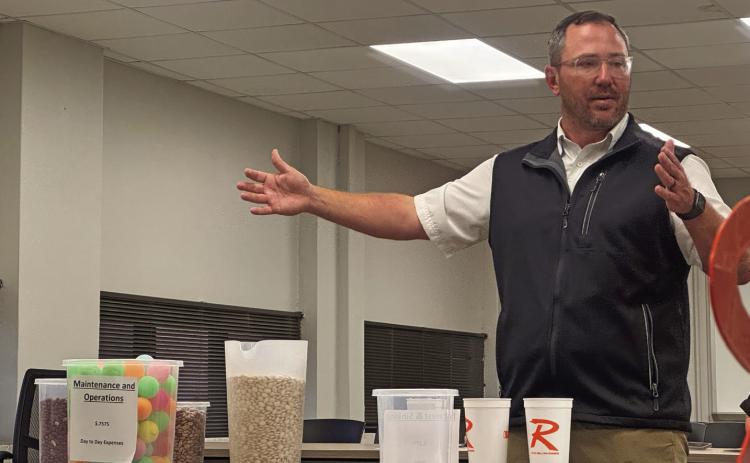 Rotan ISD Superintendent Michael Rudewick uses a variety of dried beans and a series of graduating containers to simplify the state’s education funding model during Monday night’s board meeting.