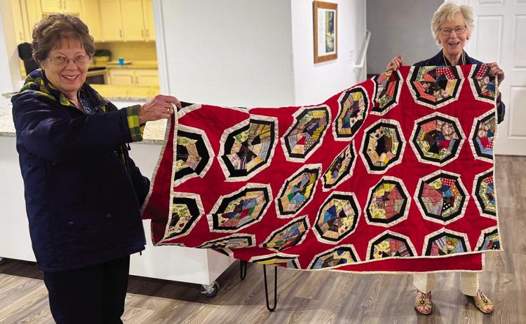 Lenice Dennis and Dot Harris show off one of Ellen Goodwi's quilts, who brought several family quilts to share during her presentation, using them to highlight how quilts preserve memory and history across generations PHOTO BY JEFF HURT