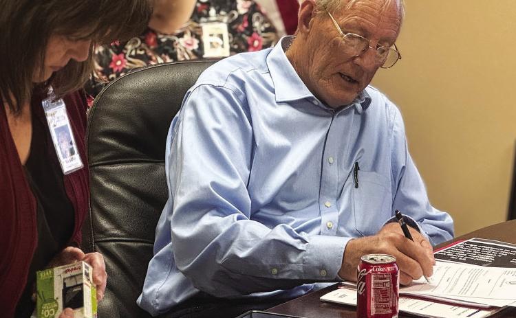 New Stonewall Memorial Hospital District board director Edmond Scott Lucast signs paperwork after taking the oath of office during the board’s Monday, May 11 meeting. PHOTO BY JEFF HURT