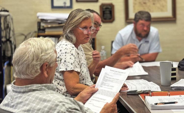 Rotan City Council members review sealed bids for repairing and renovating the cities three main water storage tanks during the July meeting.
