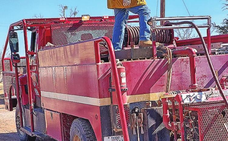 Pictured are Volunteer Firefighter Larry Coats on top of Brush 19 insuring the hose reel doesn’t jam.
