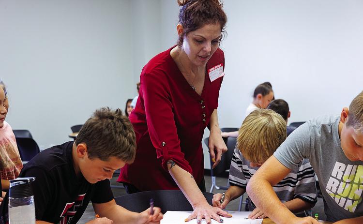 Alicia Barton with the Abilene Recovery Council lends a hand to Aspermont ISD third-graders during a project to help students learn concepts for positive decision making