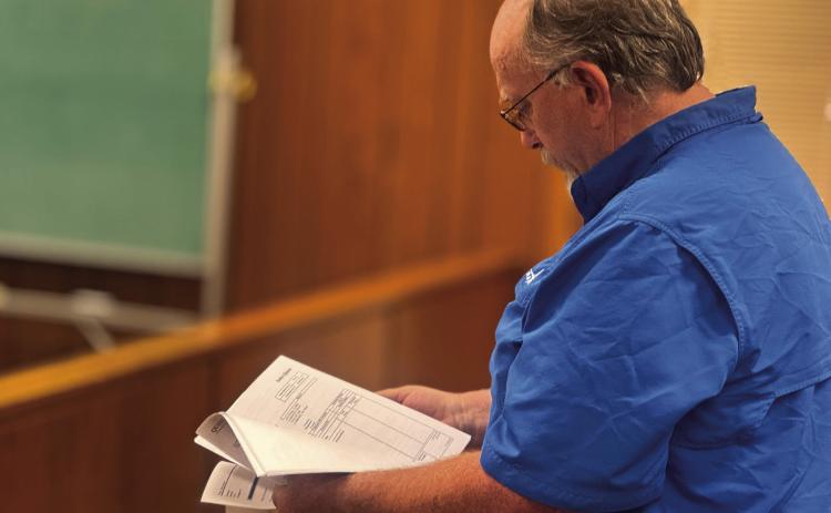 Fisher County Sheriff Pat Dickson reviews proposed bids for new patrol vehicles during Monday’s commissioners court meeting.