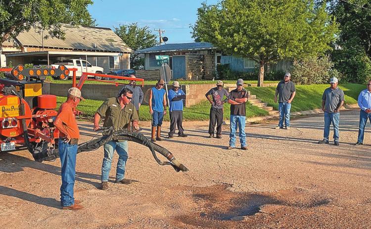 Mayor Pete Garcia and Rotan Director of Public Works Brian James watched along with fellow councilmen and city work crew as representatives with Texas Patcher demonstrated its DuraPatcher machine's ability when repairing this troublesome pothole.