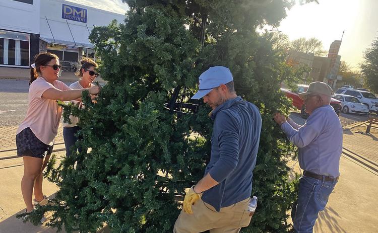 Rotan Community Service League members, Blaire Helms and Samantha Pipes (pictured left) along with Garreth Pipes and Glen Copeland (pictured Right) begins holiday preparations with the community Christmas tree going up on Monday in downtown Rotan.