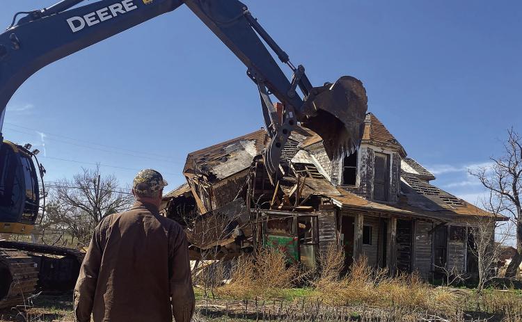 Equipment operator and contributor to the City of Aspermont's cleanup project, Michael Mims looks on as workers demolish one of the city's largest dilapidated structures on Monday. (PHOTO BY JEFFHURT)